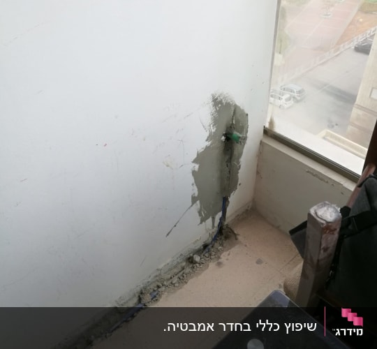 קיר עם תיקון טיח וצינור חשוף ברצפה